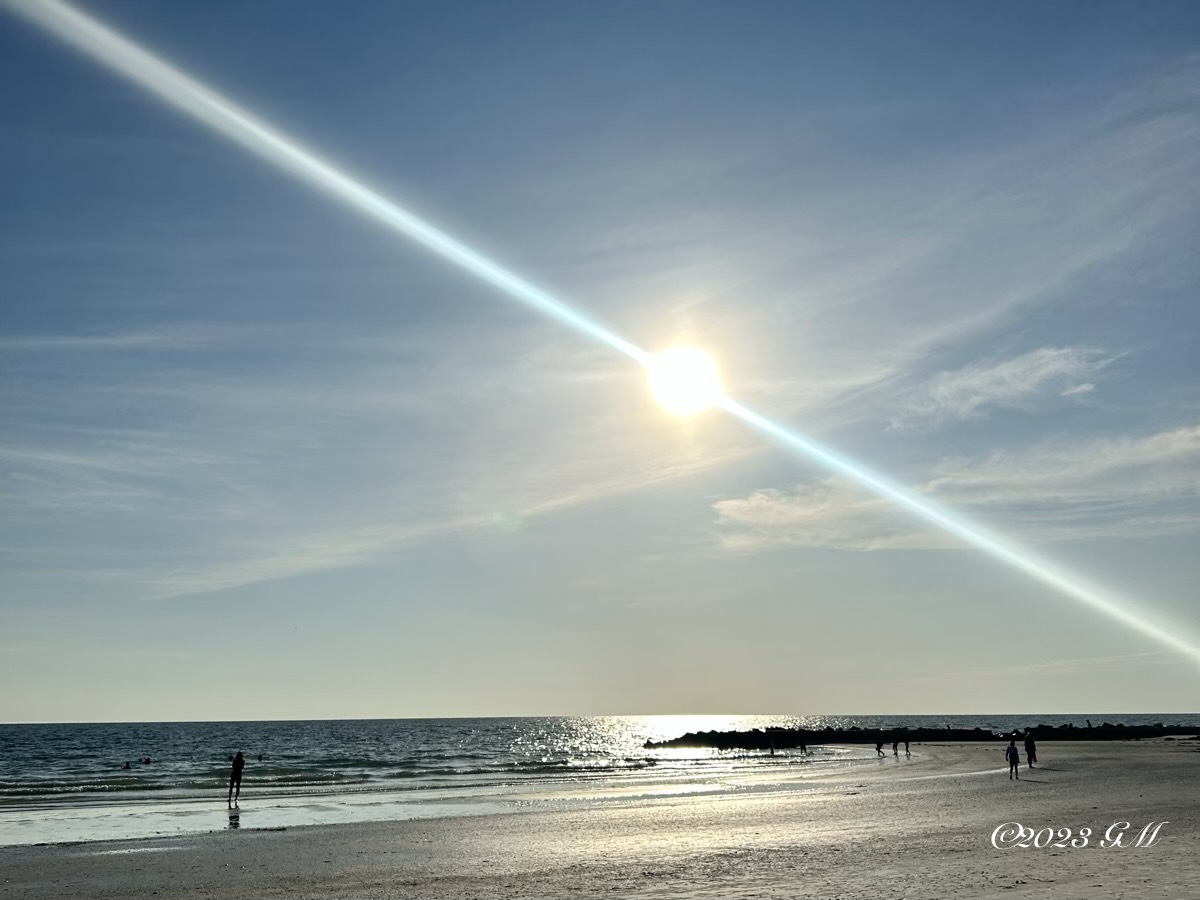 Sun near setting over water and a beach