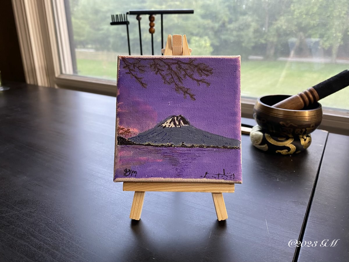 Finished painting of Sunset on Fuji being displayed on a desk near a window with a singing bowl in the background